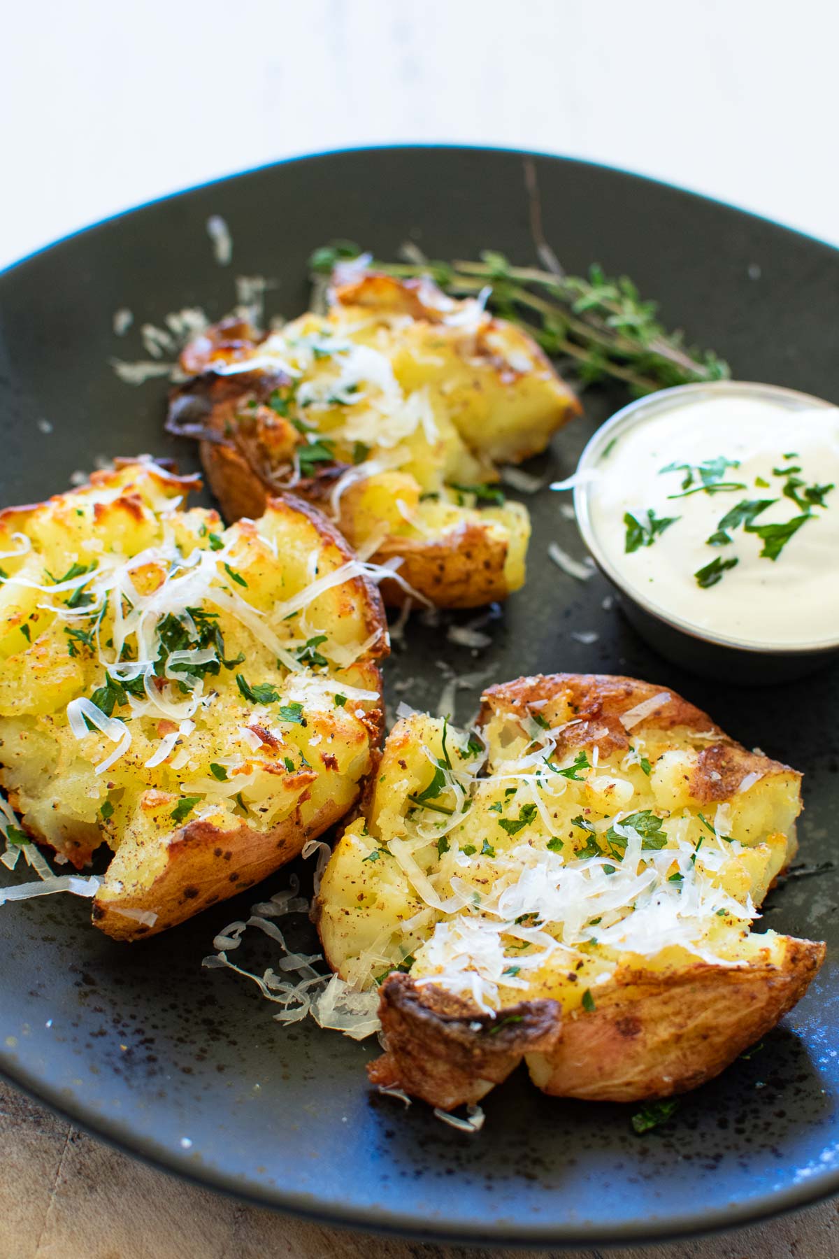 A black plate with cheesy smashed potatoes.