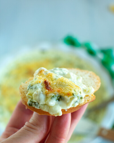 a cracker with spinach and artichoke dip.