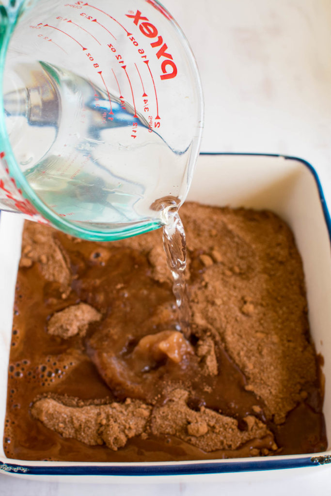 Water being poured over a chocolate pudding cake.