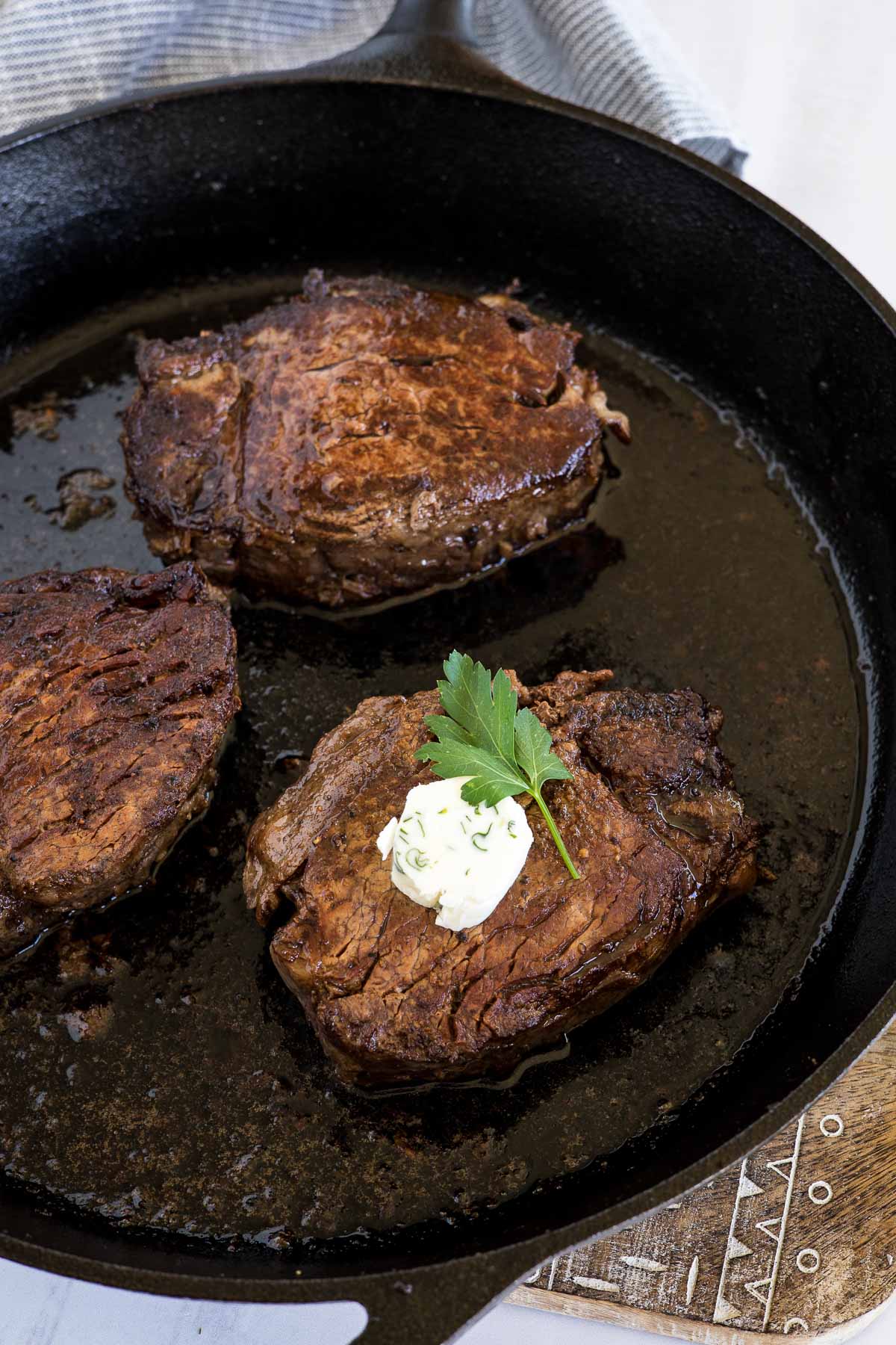 Seared tenderloin steak with butter on top in a skillet.
