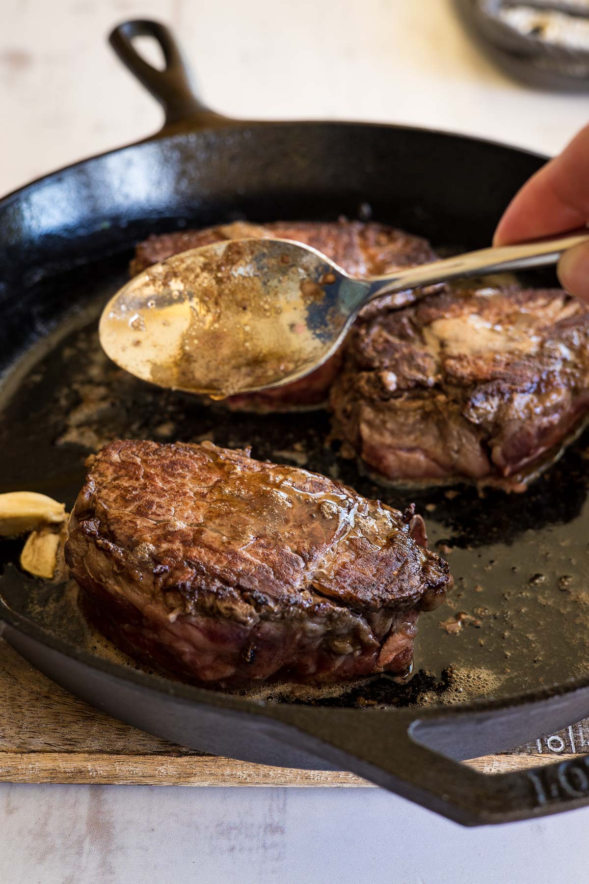 Spooning butter over cooked steaks.