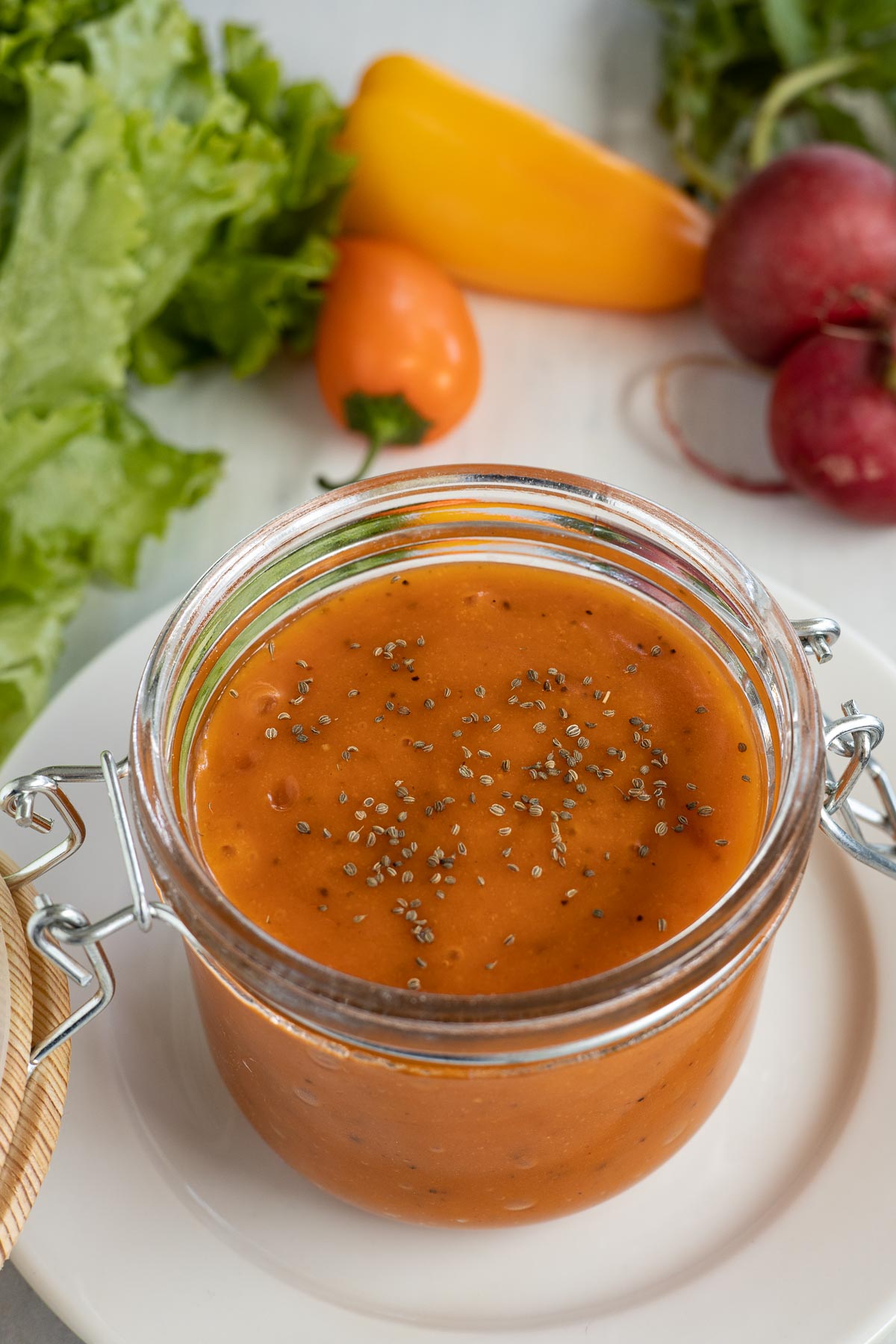 A jar of French dressing with green salad ingredients.