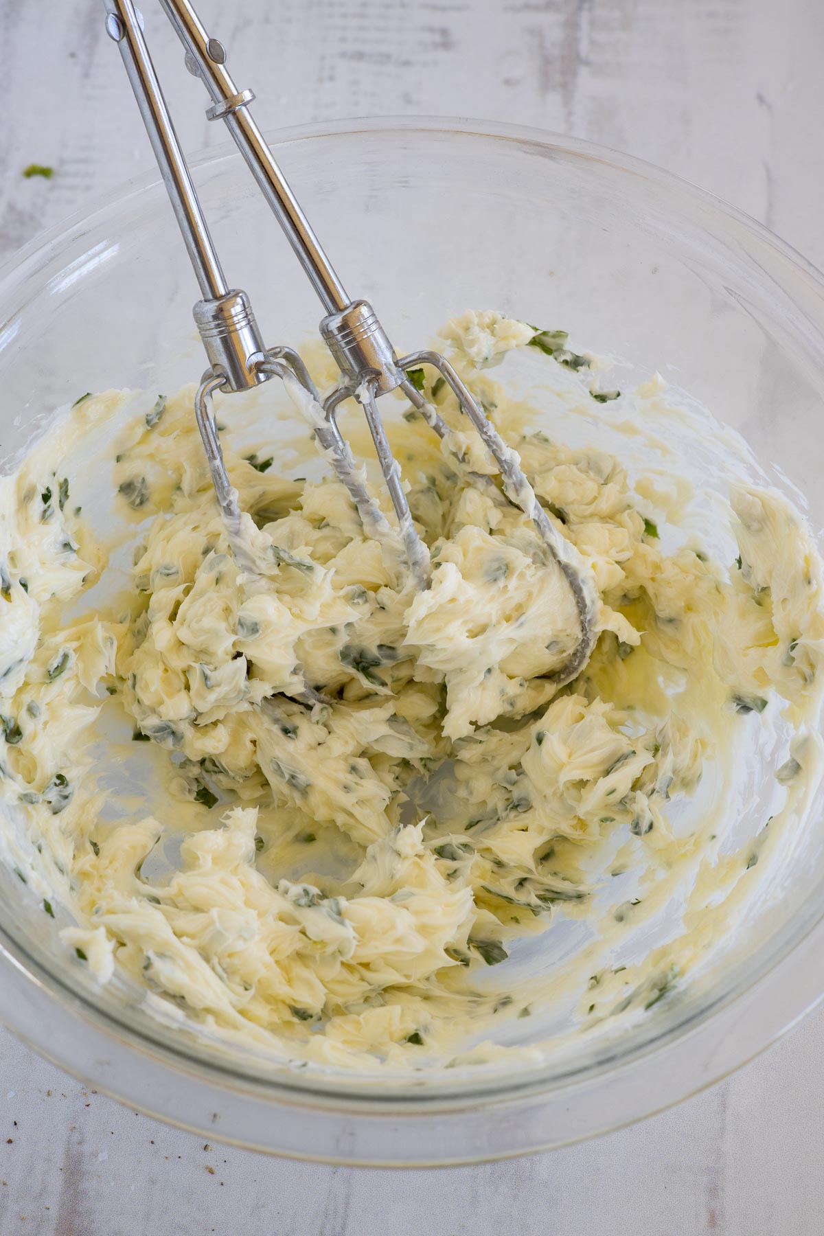 Mixed herb butter in a bowl with beaters.
