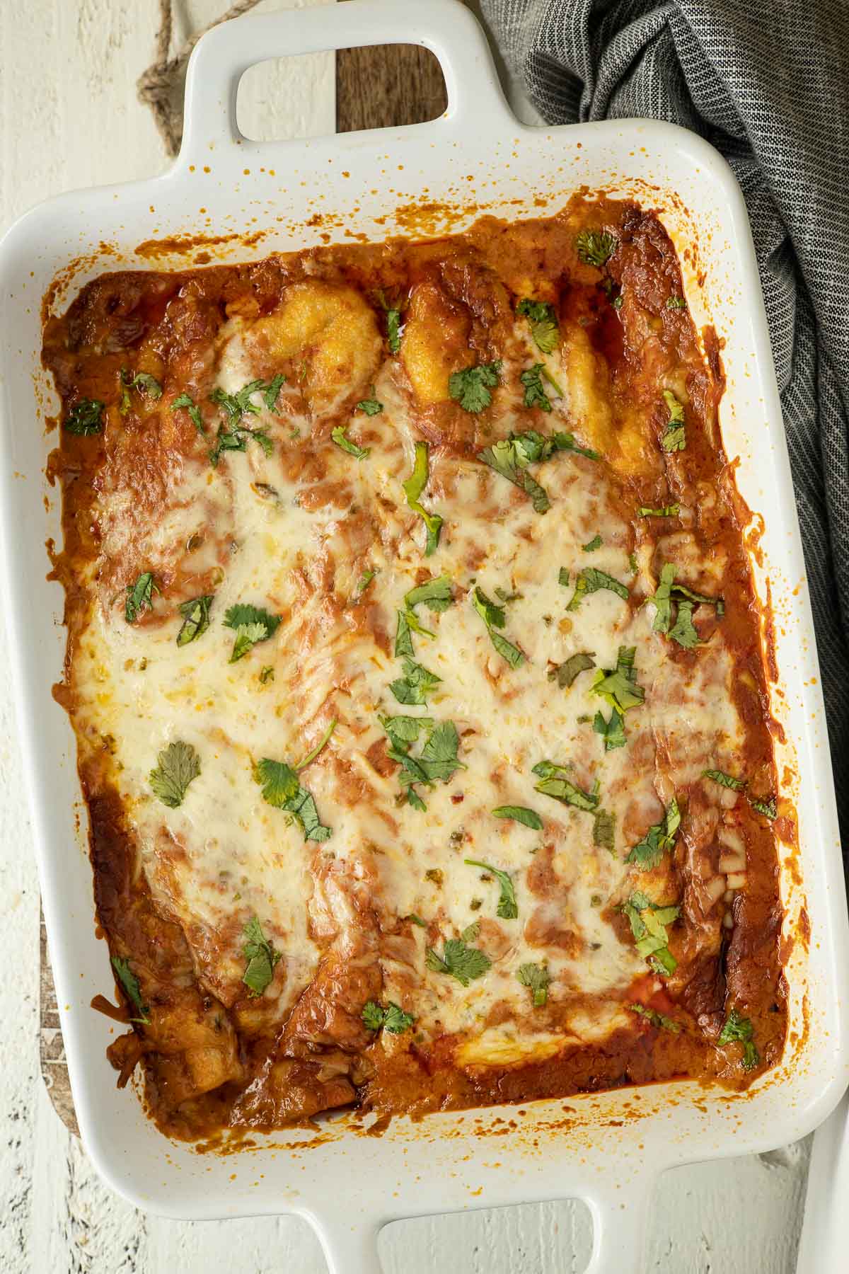 Baked beef enchiladas in red sauce with cheese and cilantro.