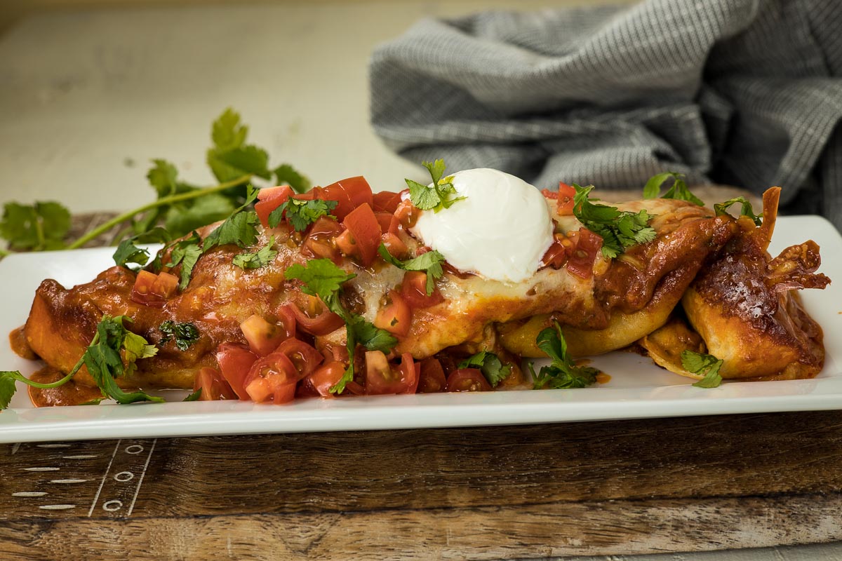 Shredded beef enchiladas on a white plate.