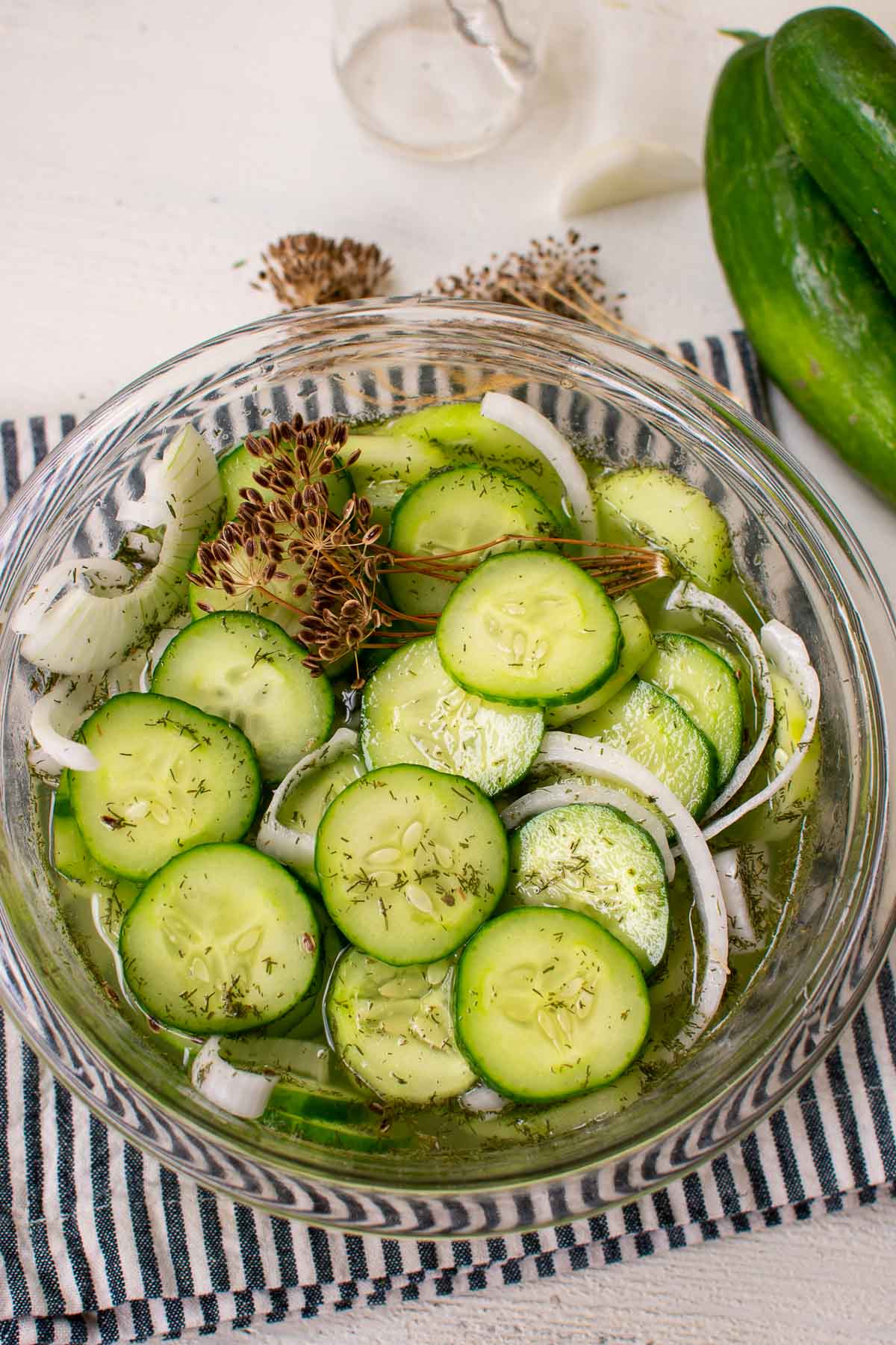 Sliced cucumbers and onions in vinegar in a glass bowl.