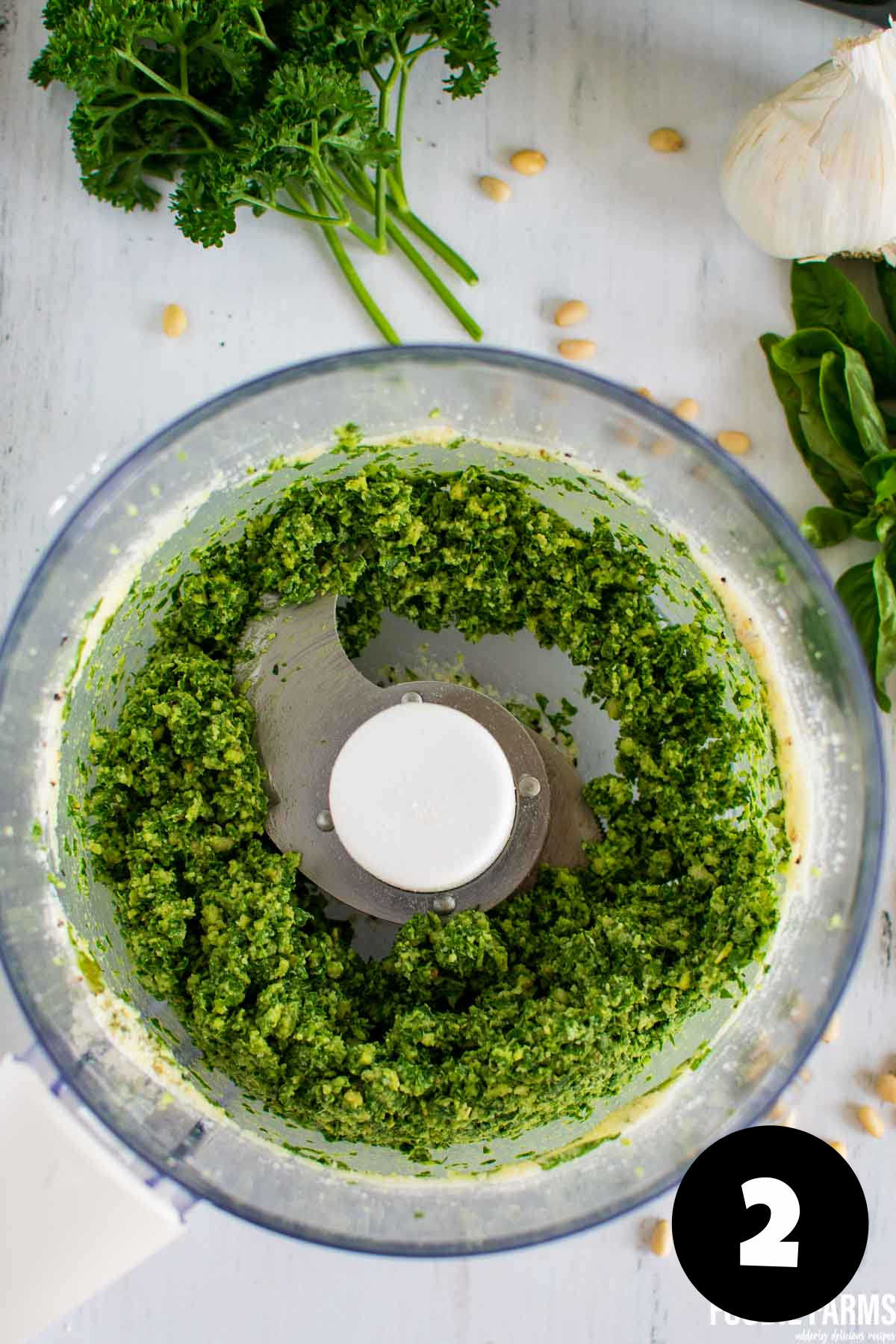 Chopped green herbs in a food processor.