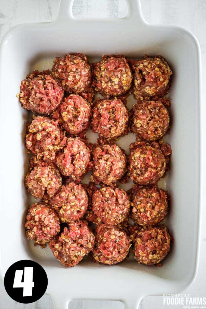 Raw meatballs in a white baking dish.