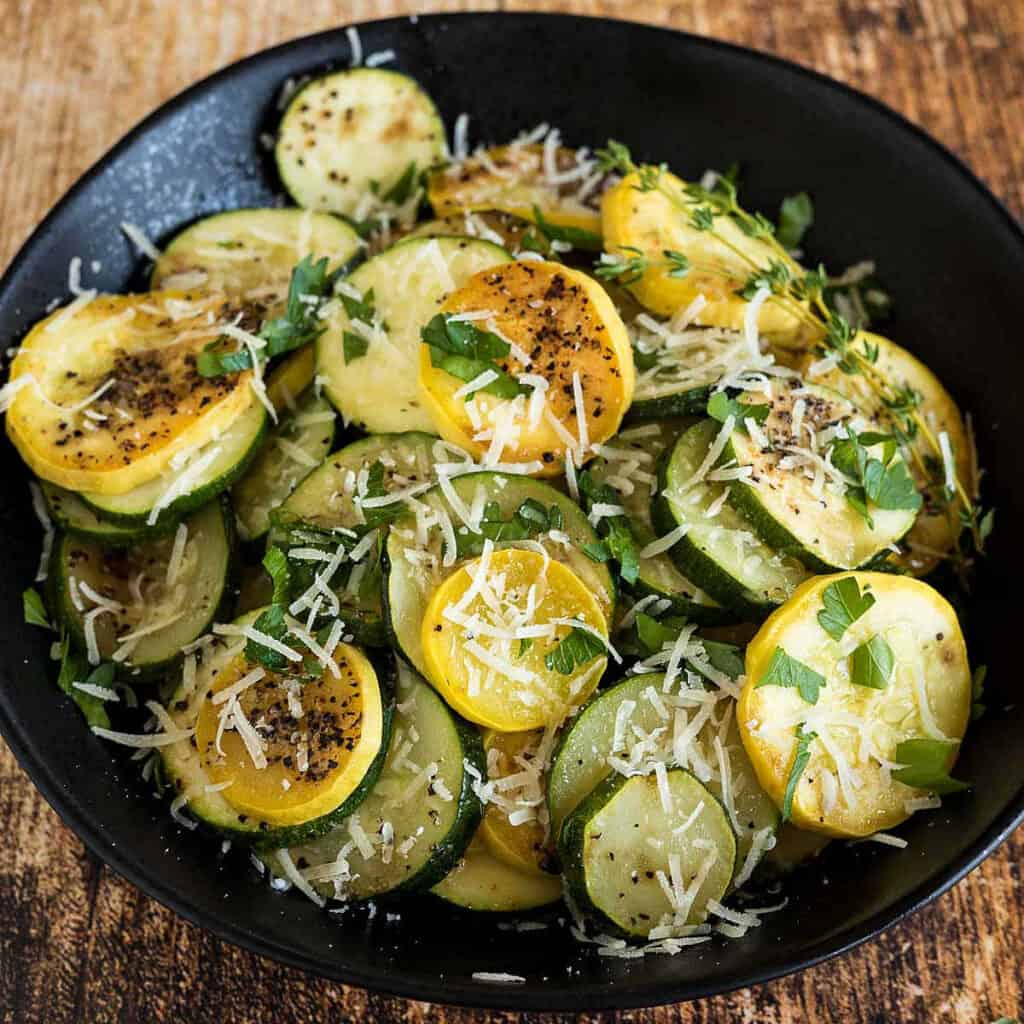 Zucchini and yellow squash cut into circles sprinkled with grated parmesan cheese and fresh parsley.