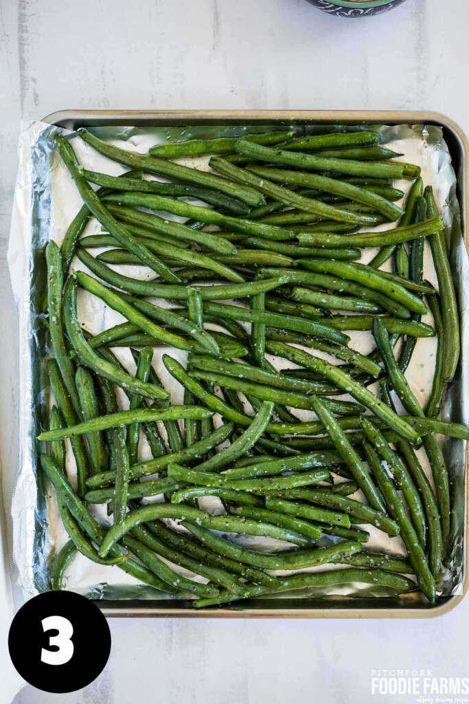 Raw green beans spread on a baking sheet.