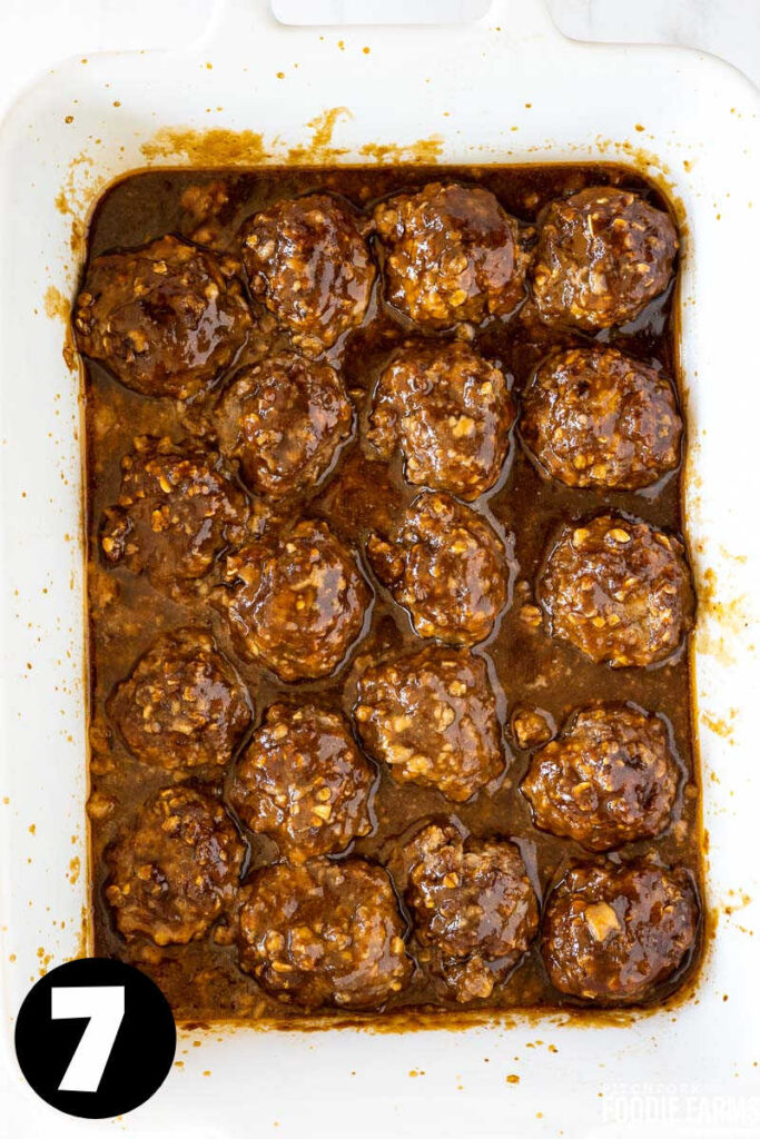 Baked meatballs in sweet and sour sauce in a white baking dish.