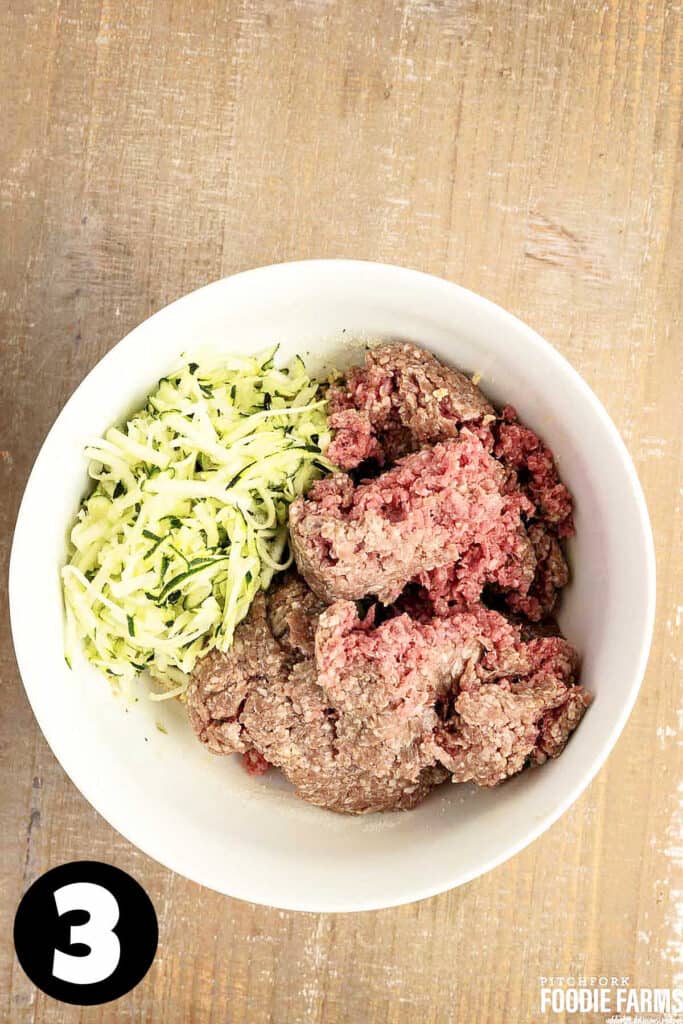Grated zucchini and ground beef in a mixing bowl.