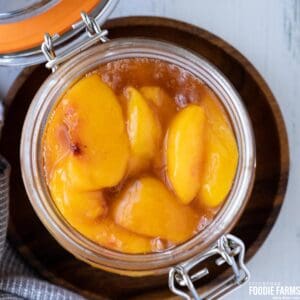 Fresh sliced peaches in peach pie filling in a glass jar.