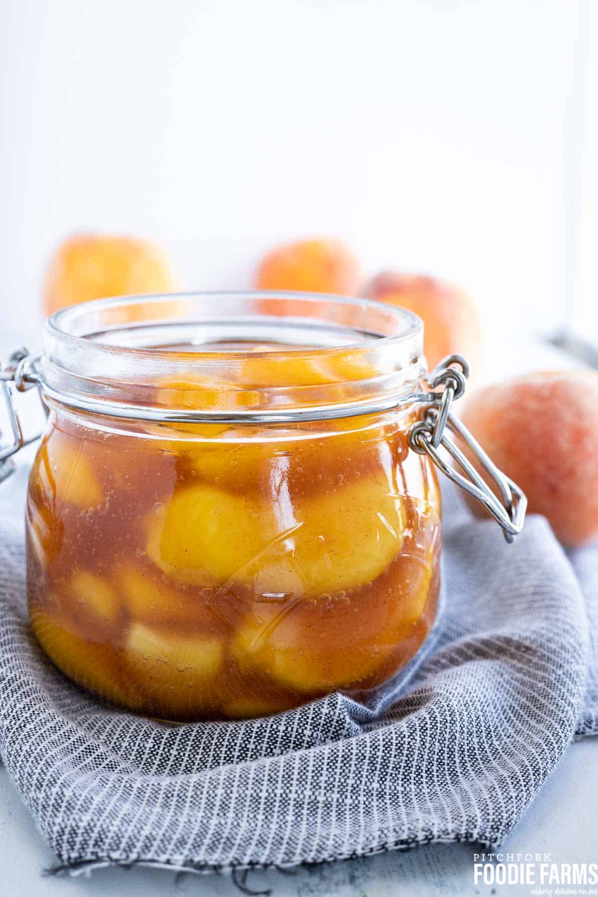 Peach pie filling in a jar sitting on a blue and white napkin.