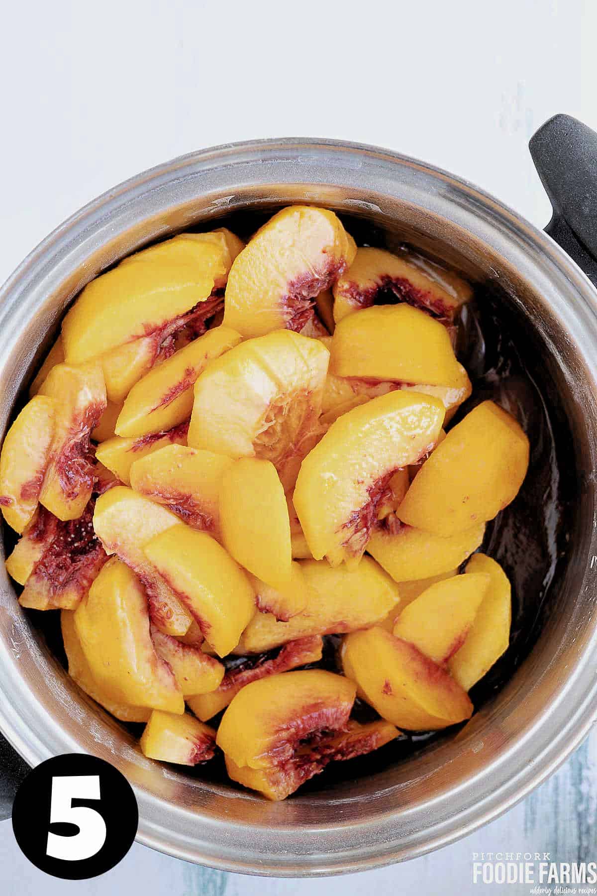 Sliced fresh peaches in a saucepan.