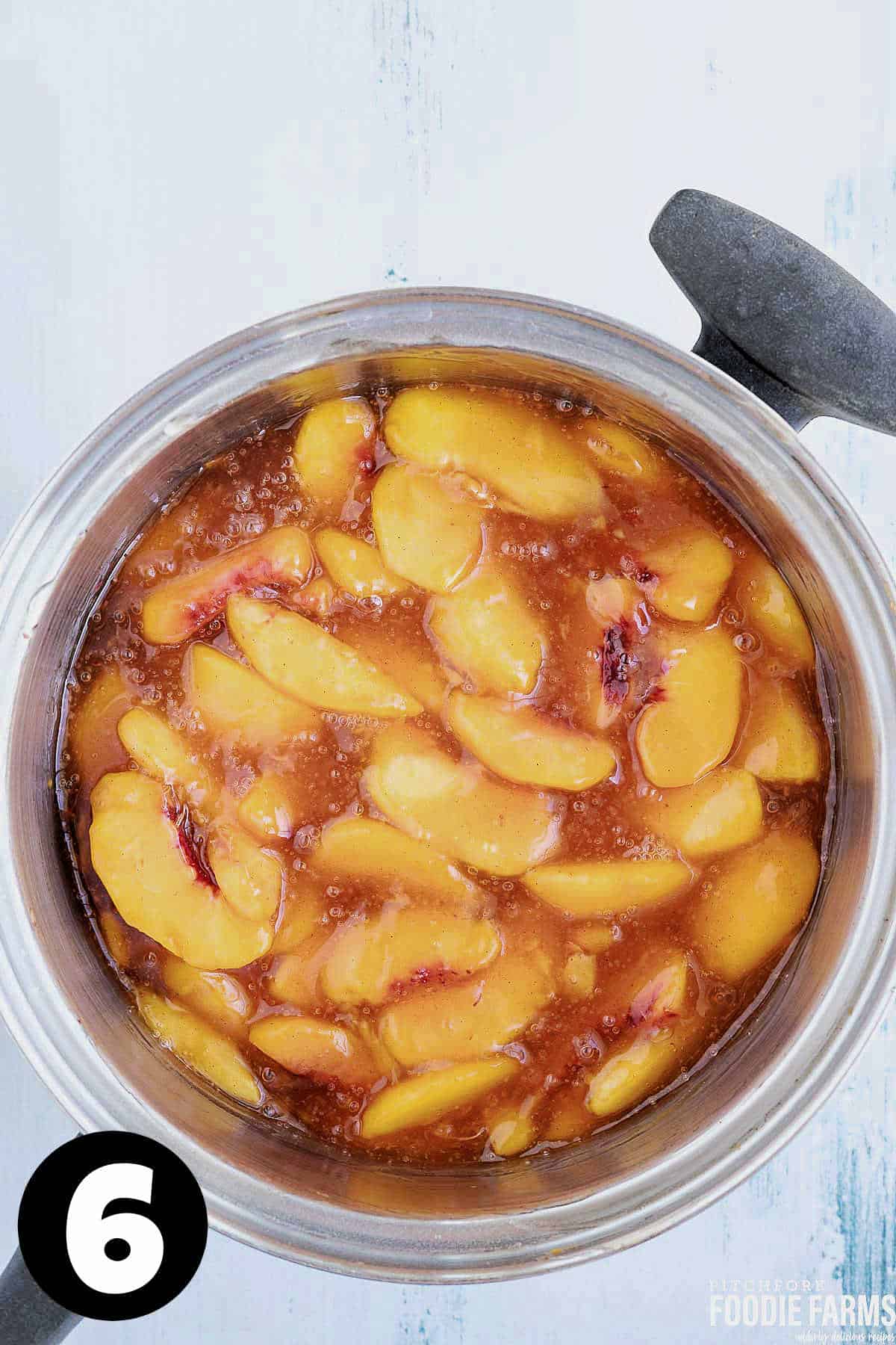 Sliced peaches in pie filling sauce in a saucepan.