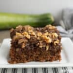A square of chocolate zucchini cake with walnuts and chocolate chips on top.