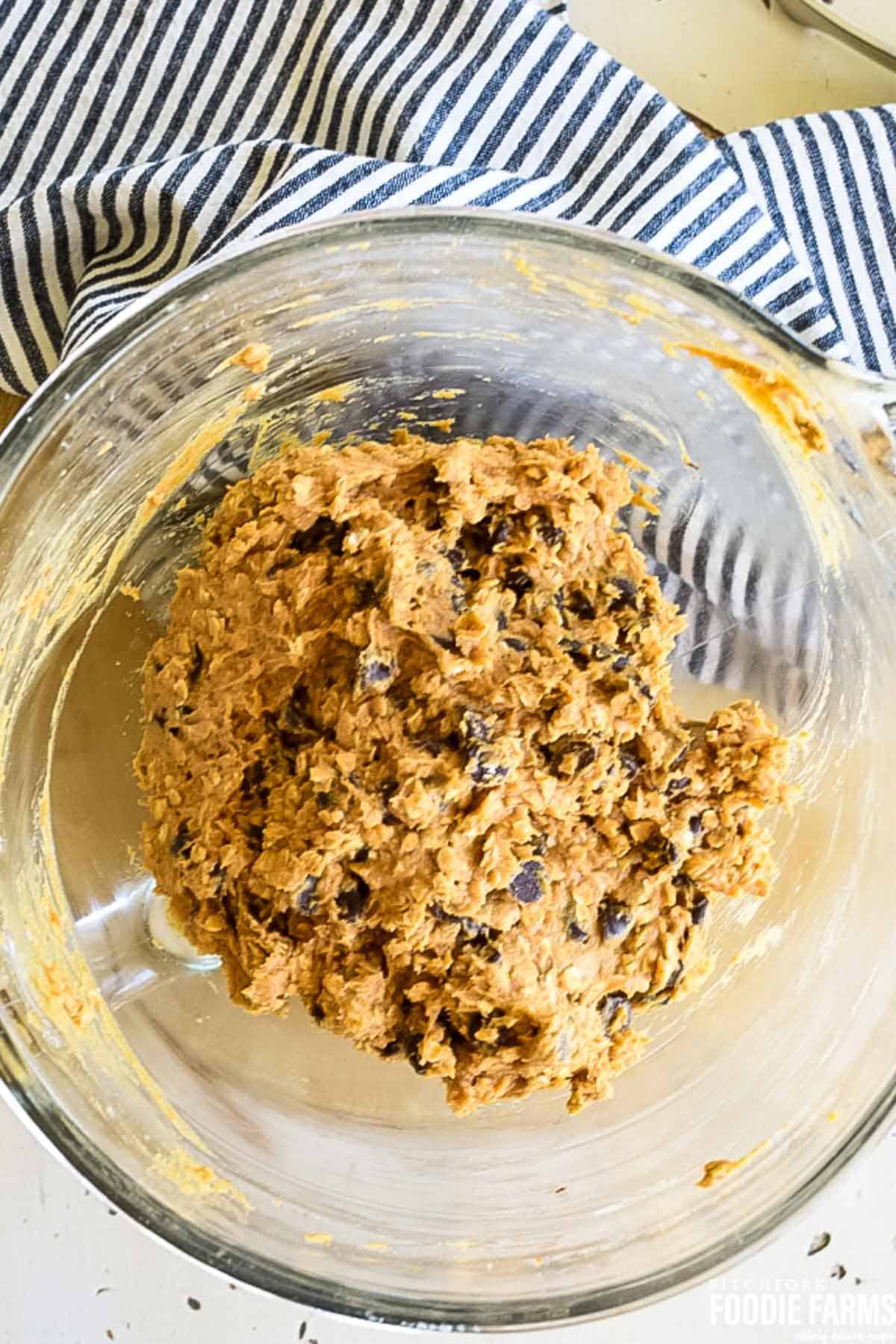 A glass mixing bowl with cookie dough.
