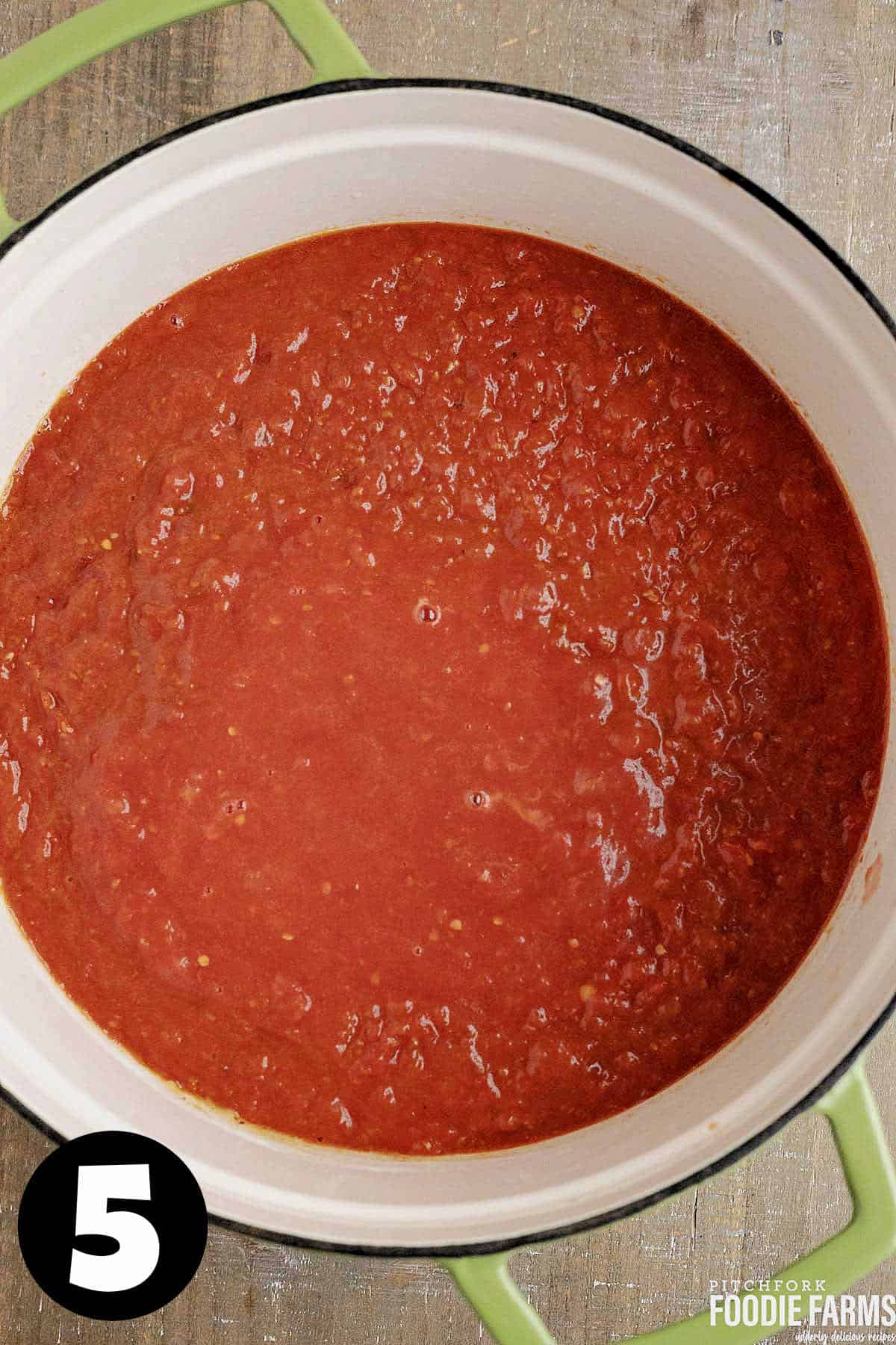 Fresh tomato puree in a large white pot to make tomato soup.