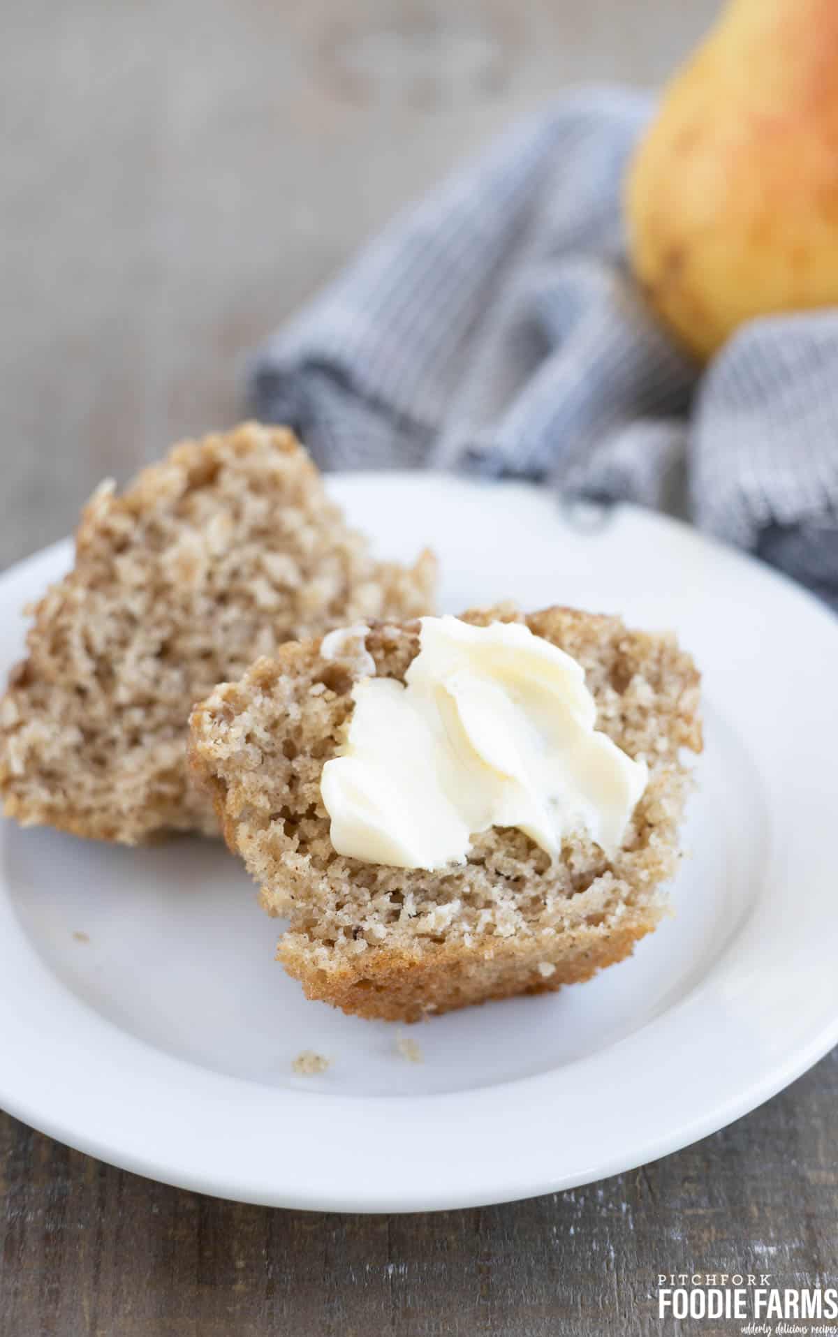 A quick bread muffin cut in half with butter spread on it.