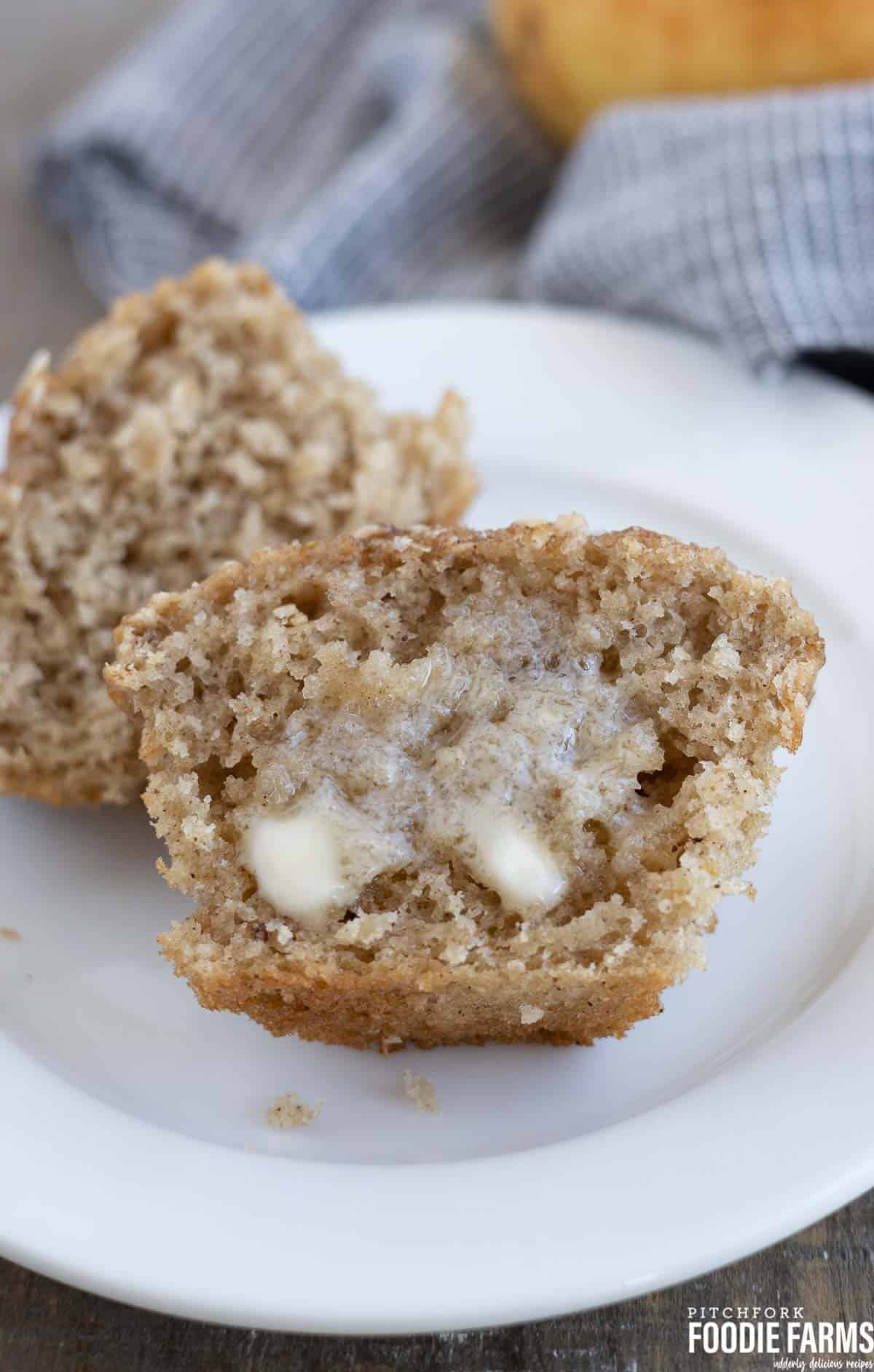 A cinnamon pear muffin cut in half with melted butter spread on it.
