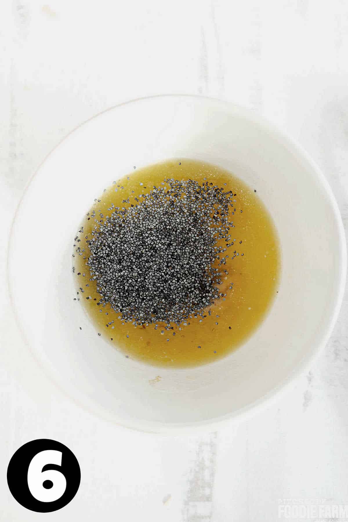 Melted butter, poppy seeds, and other spices in a white mixing bowl.