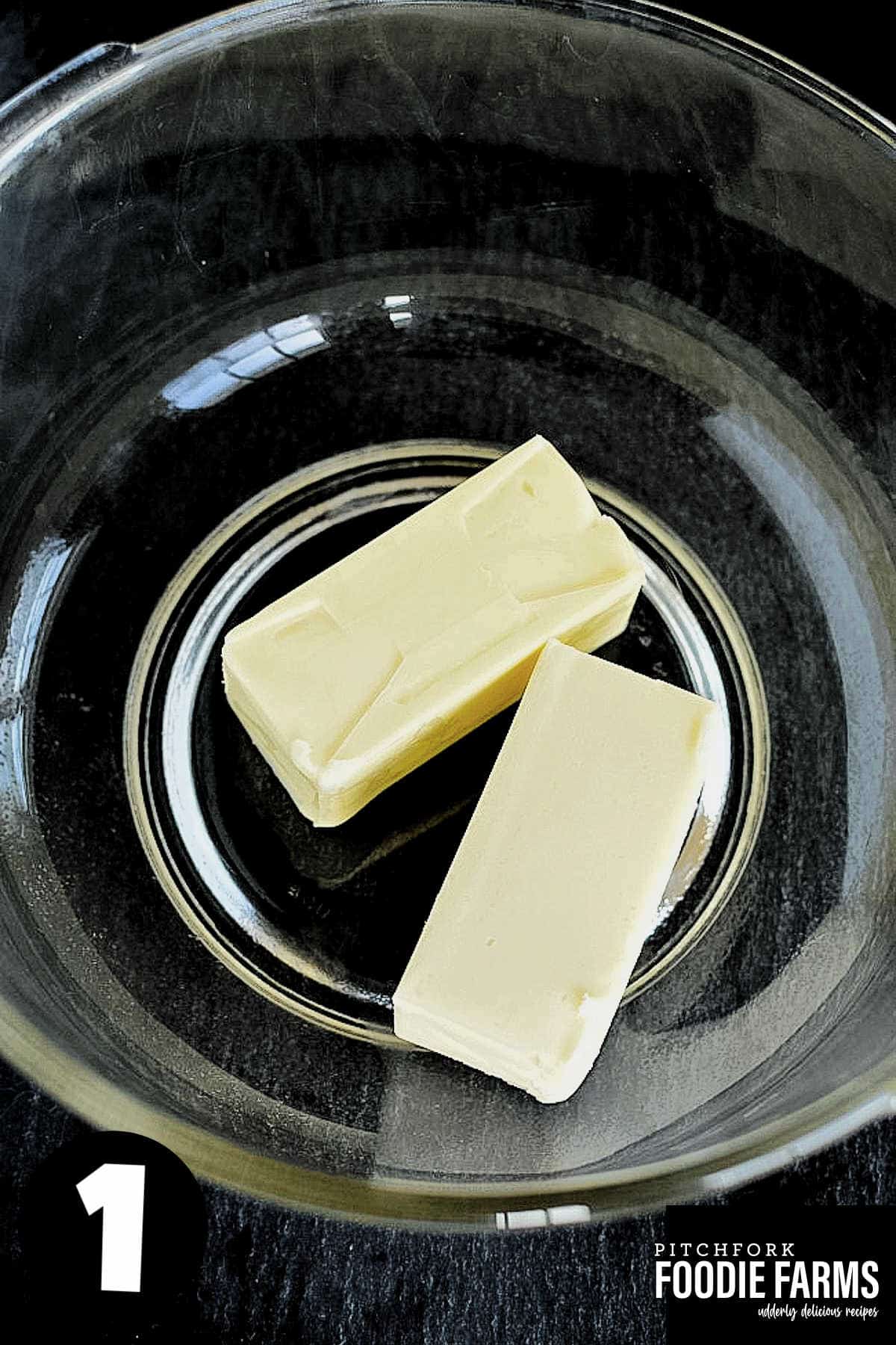 Two cubes of butter in a glass bowl.