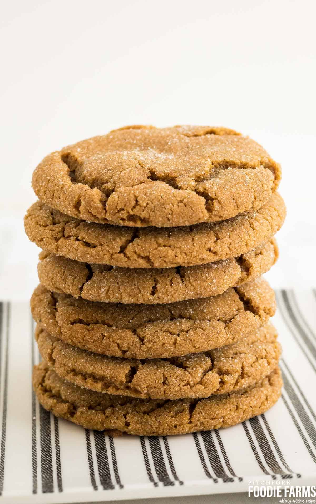 A stack of baked gingersnap cookies on a striped plate.