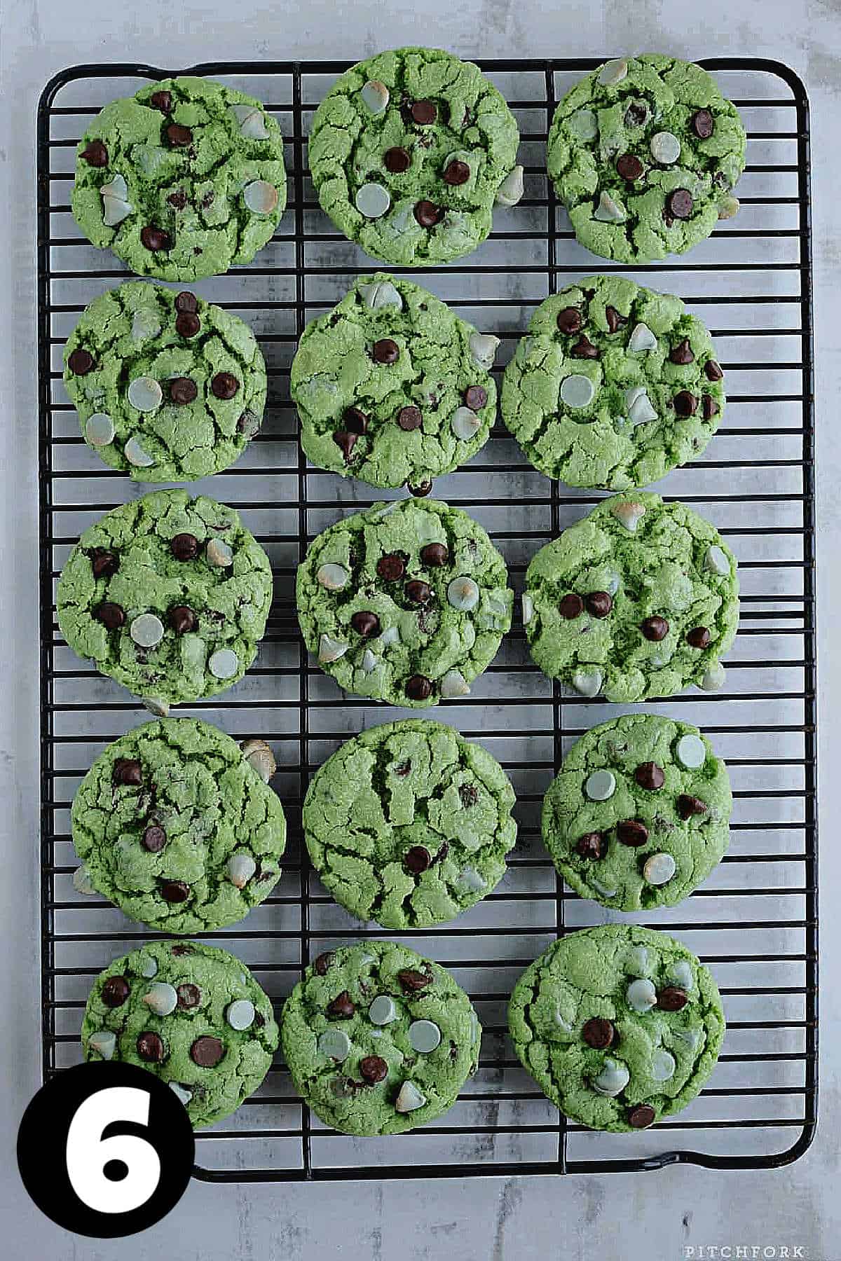 Green mint chocolate chip cookies on a wire cooling rack.