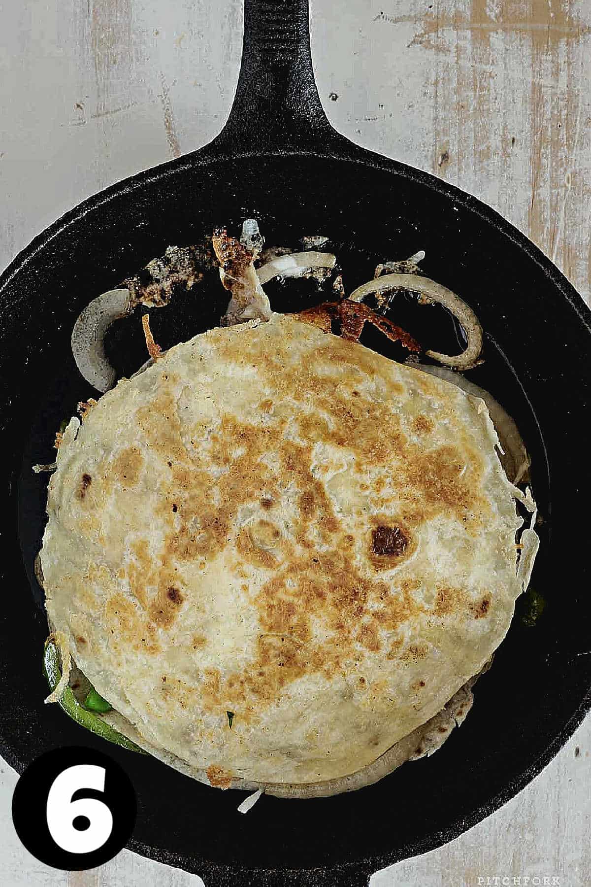 A browned quesadilla in a skillet.