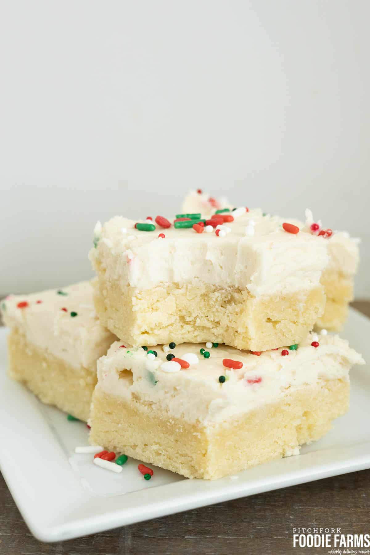 A stack of sugar cookie bars with red and green Christmas sprinkles on frosting.