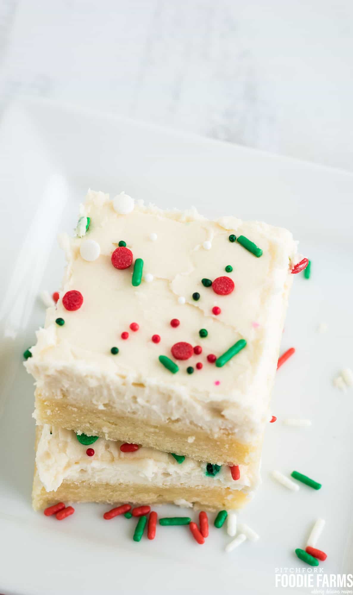 A stack of sugar cookie bars cut into squares and sprinkled with holiday sprinkles.