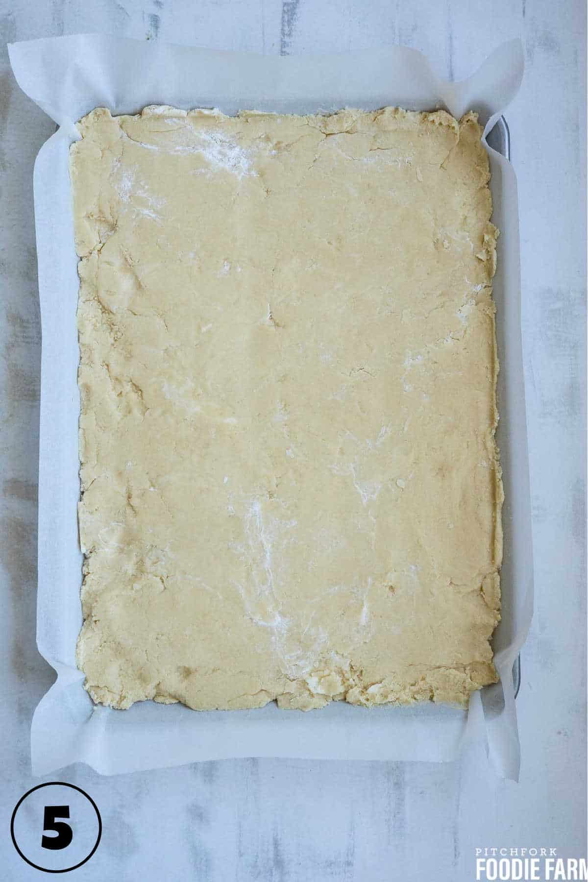 Sugar cookie dough pressed in a sheet pan.