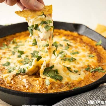 Chili cheese bean dip with a tortilla chip dipped in.