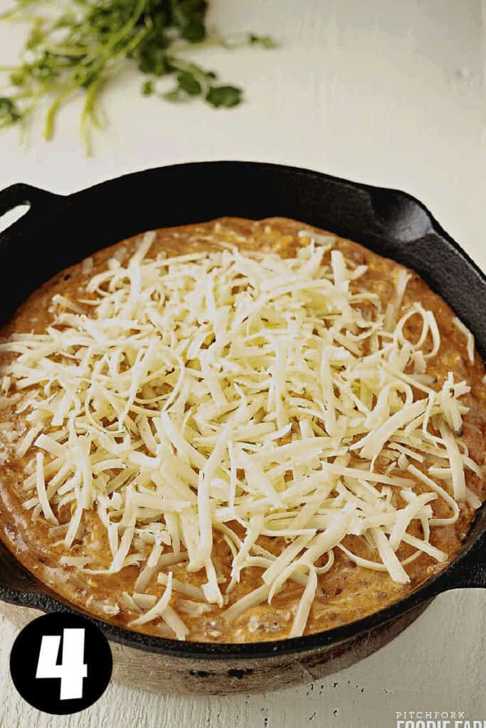 Chili cheese dip with grated pepper jack cheese on top.