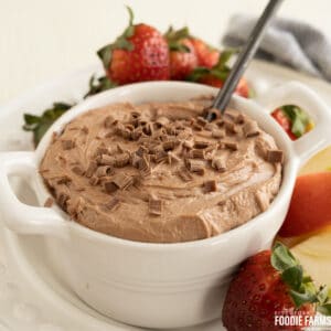 Chocolate dip with chocolate curls on top surrounded by fresh fruit.