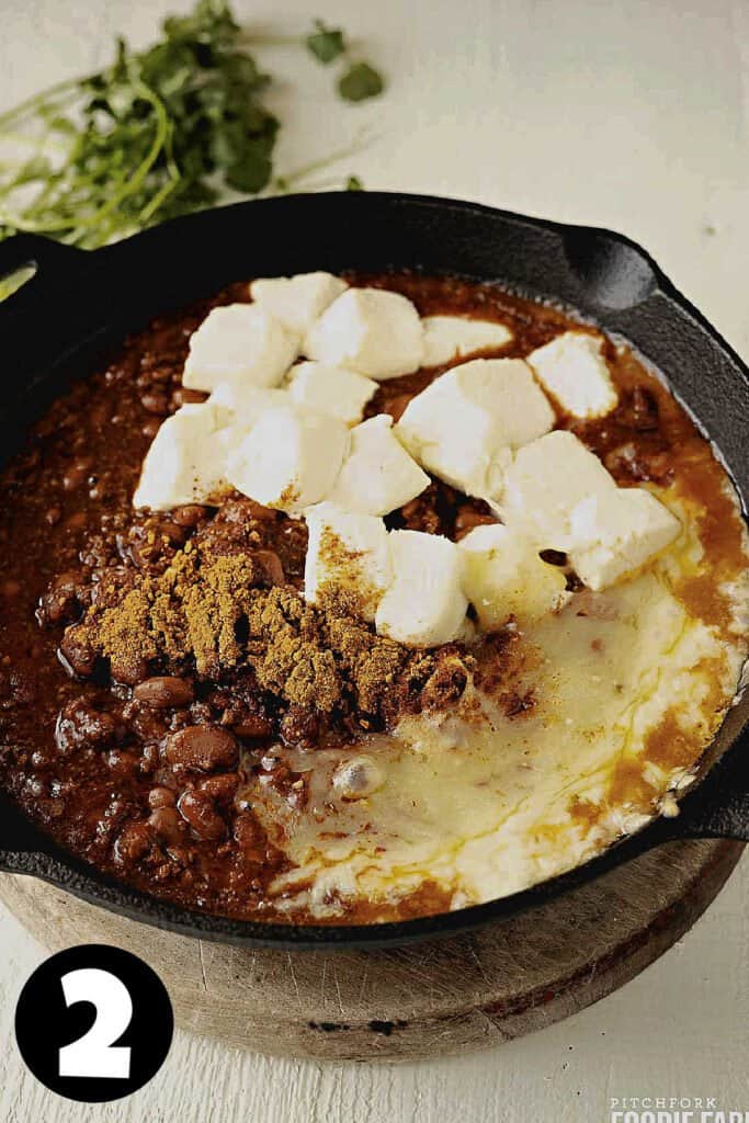 Baked cream cheese, canned chili, and melted cheese in a skillet.