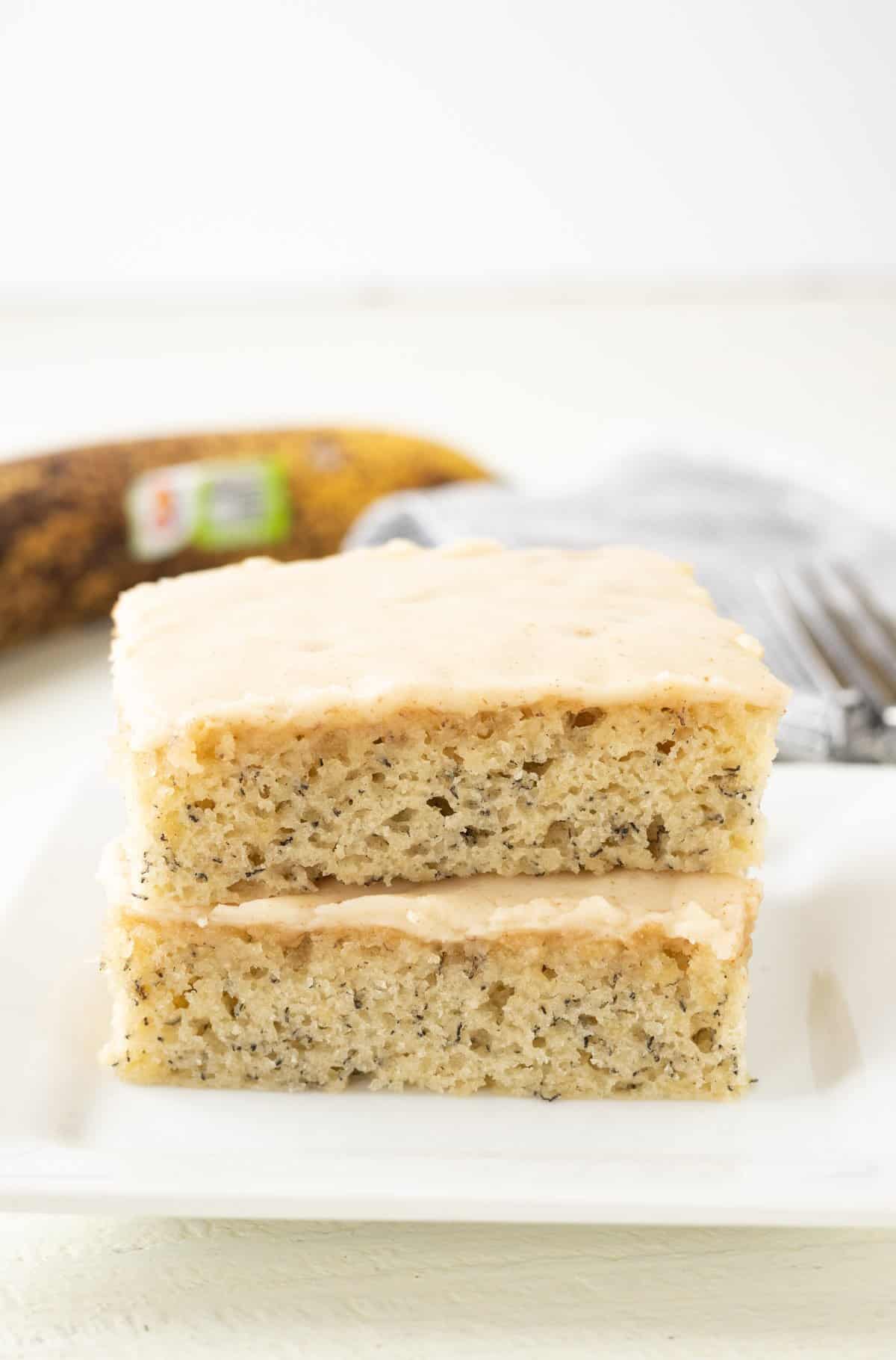 Banana bars cut into square and frosted with cream cheese icing on a plate.