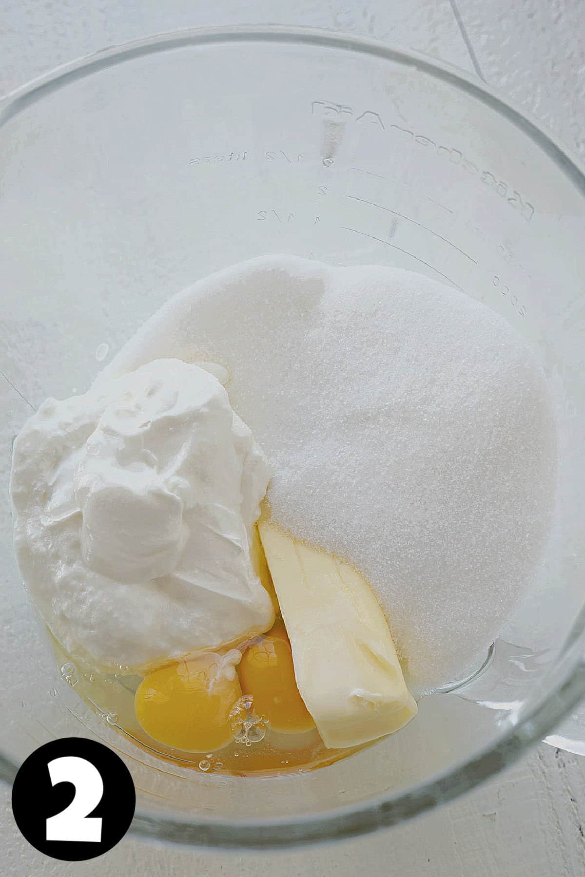 Sour cream, butter, eggs, and sugar in a mixing bowl.