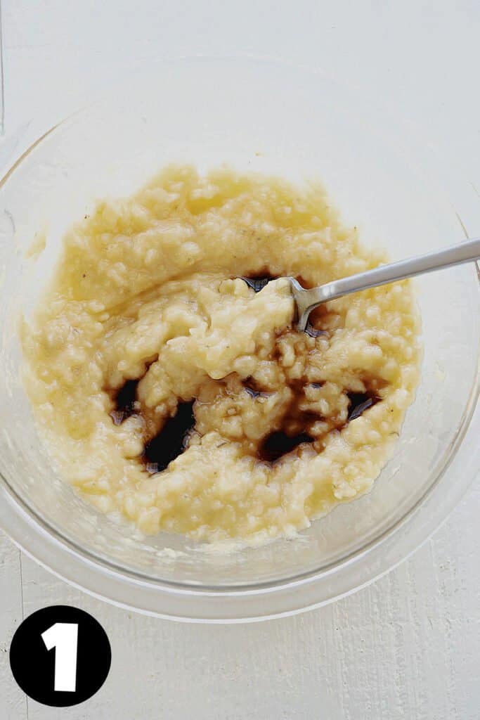 Smashed overripe bananas and vanilla in a glass bowl.