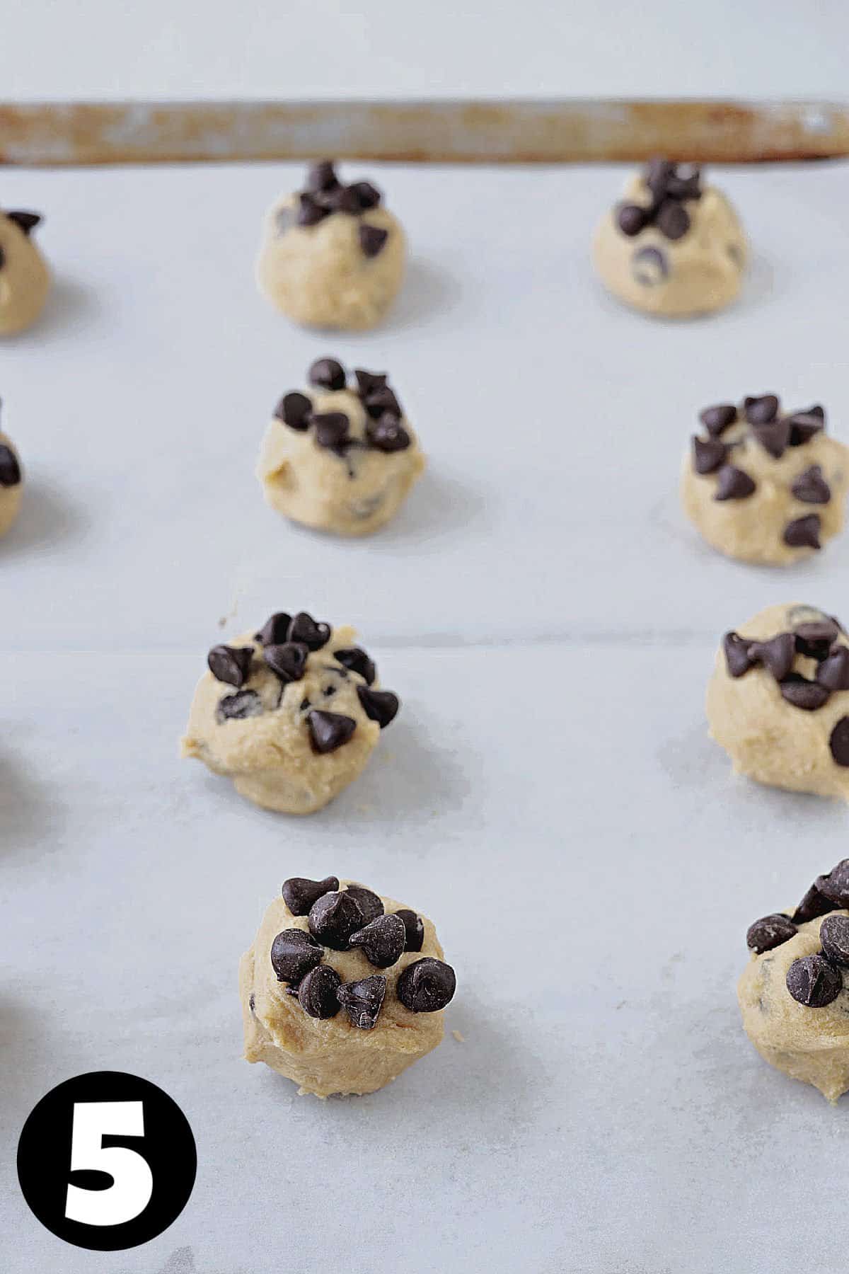 Chocolate chip and peanut butter cookie dough dropped on a parchment lined baking sheet.