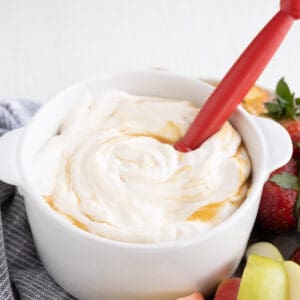 A white dish with apple dip with salted caramel swirled on top.
