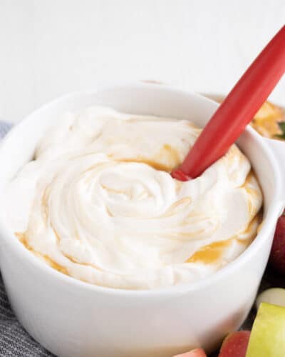 A white dish with apple dip with salted caramel swirled on top.