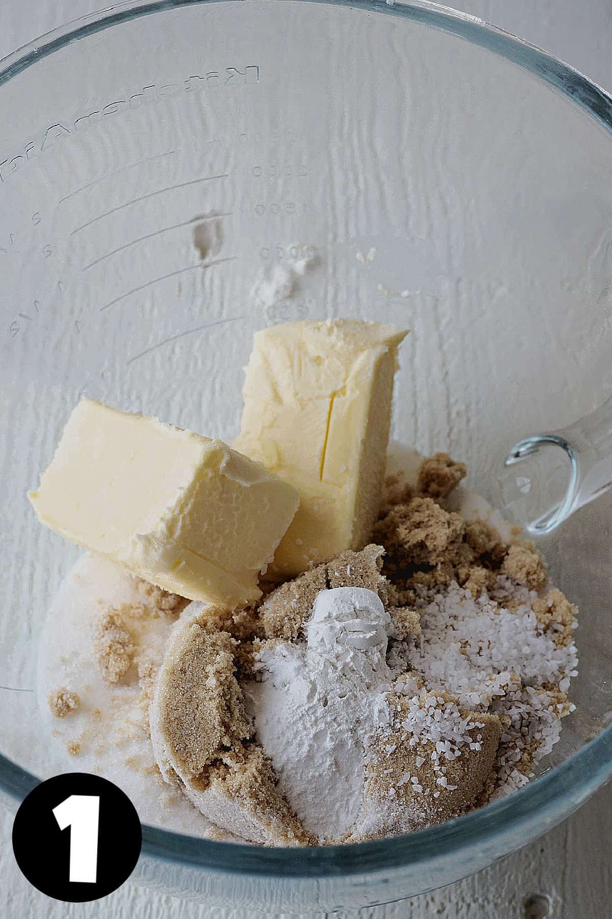 A stand mixer bowl with butter, brown sugar, granulated sugar, baking soda, and baking powder.