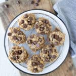 Banana cookies with chocolate chips and oatmeal on a cooling rack on a white plate.