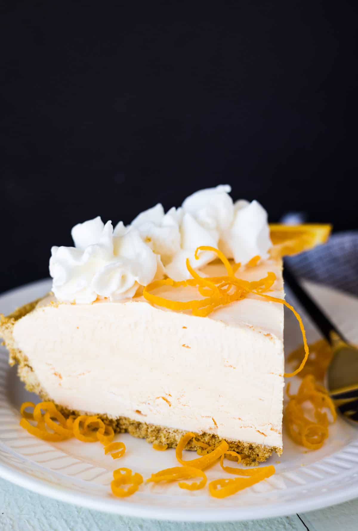 A piece of fluffy cheesecake with orange zest on top.