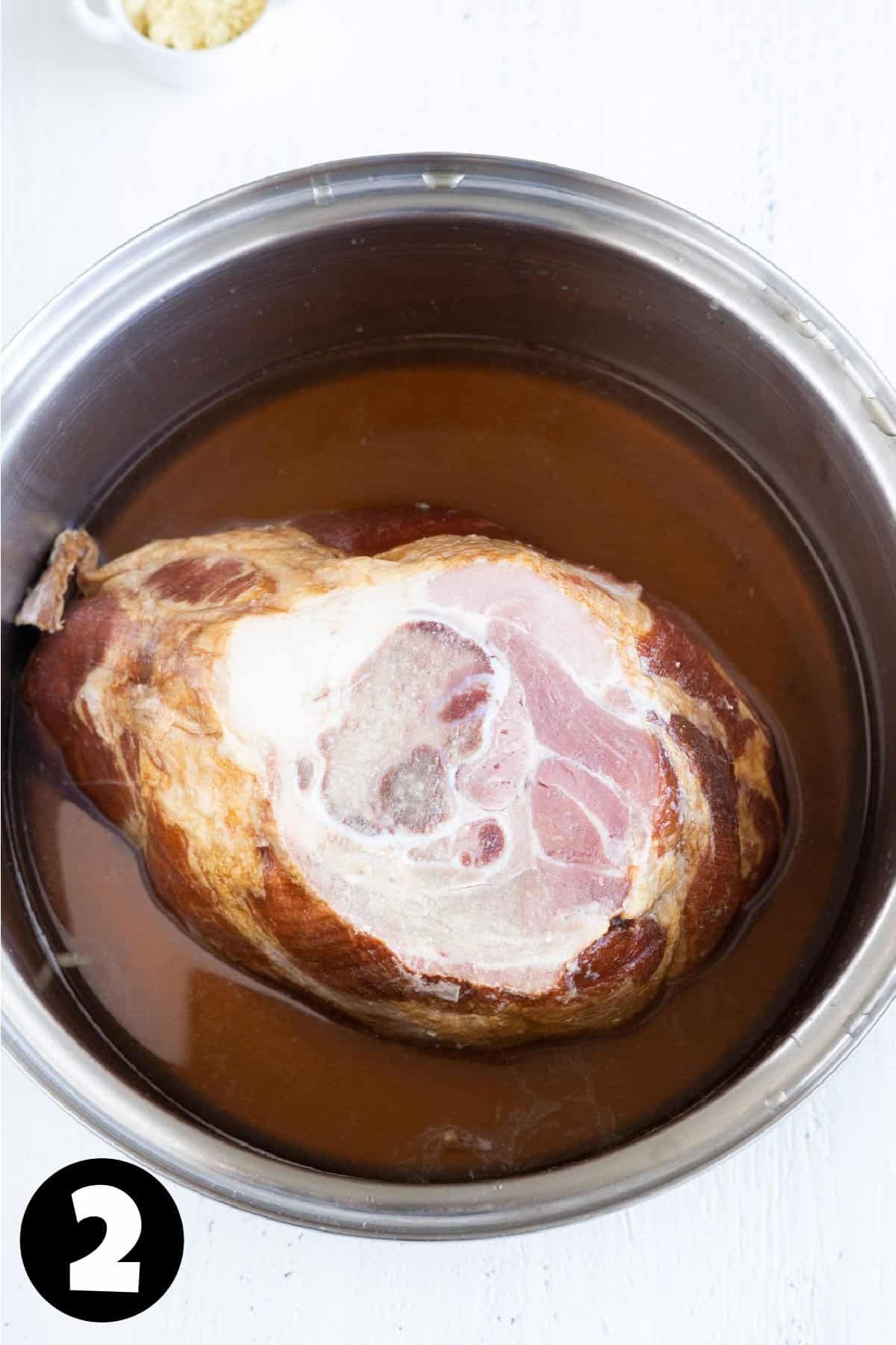 A ham in a pot with cider vinegar and brown sugar.