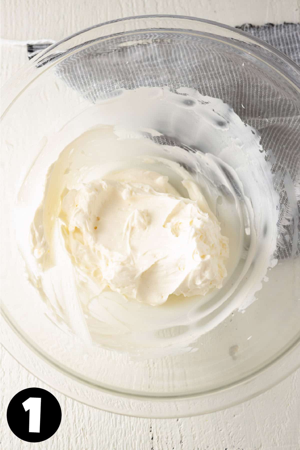 Fluffy whipped cream cheese in a glass mixing bowl.