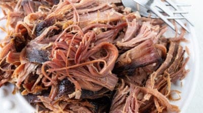A plate of shredded ham with two forks.