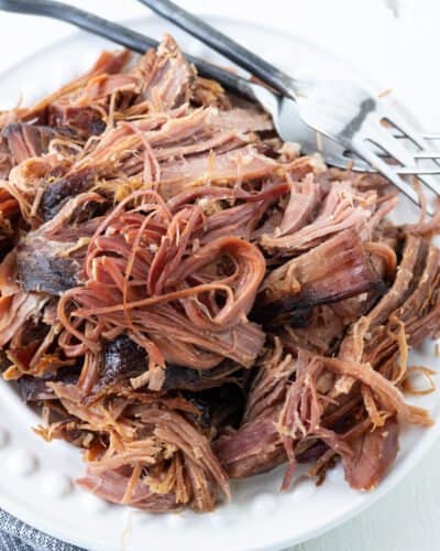 A plate of shredded ham with two forks.